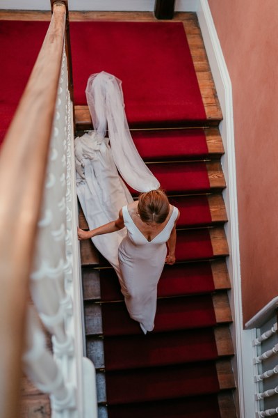 Bride on staircase walking down veil train following