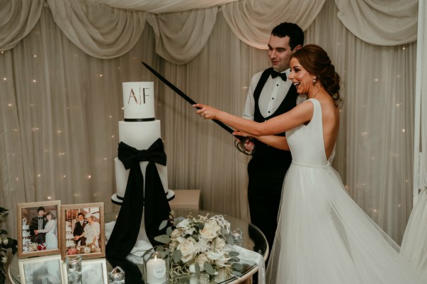 Bride and groom cut the cake with sword AF initials white