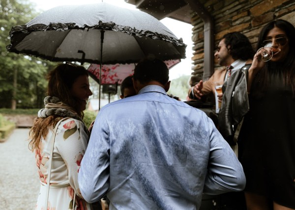 Guests hold up umbrellas protecting themselves from the rain