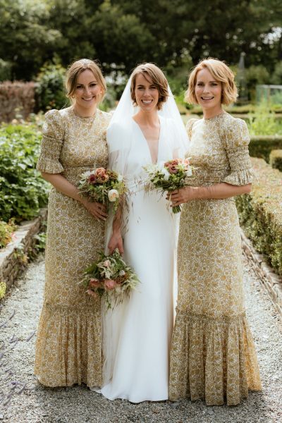 Bride stands with bridesmaids holding bouquet of flowers