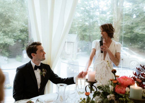 Bride gives speech to groom they hold hands during ballroom setting