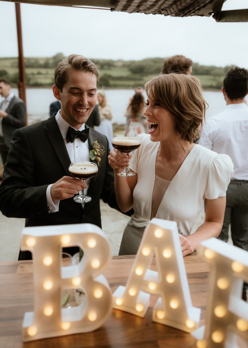 Light sign in front of couple drinking espresso martinis