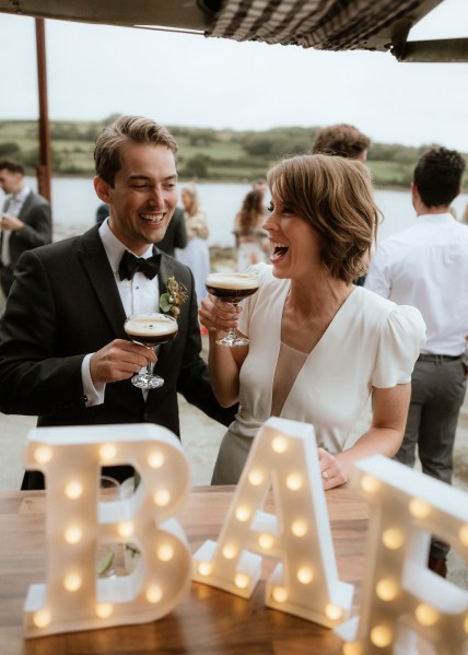 Light sign in front of couple drinking espresso martinis