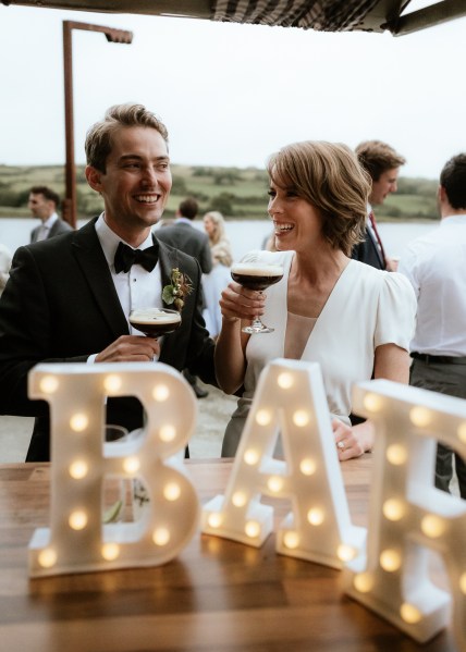 Light sign in front of couple drinking espresso martinis