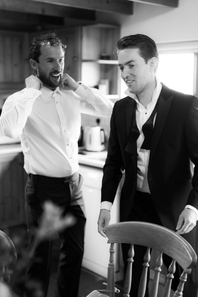 Black and white image of groom and groomsman getting ready