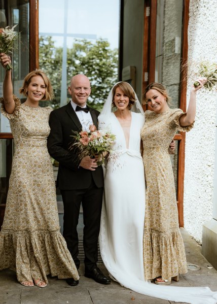 Bridesmaids bride and father pose for a photo