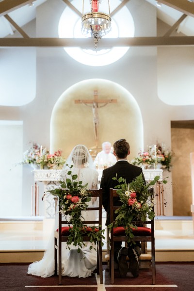 Couple from behind at alter bride and groom sitting seated