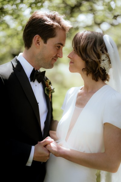 Bride and groom look at each other in forest setting