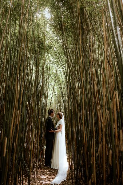 Bride and groom pose amongst the trees in forest holding each other