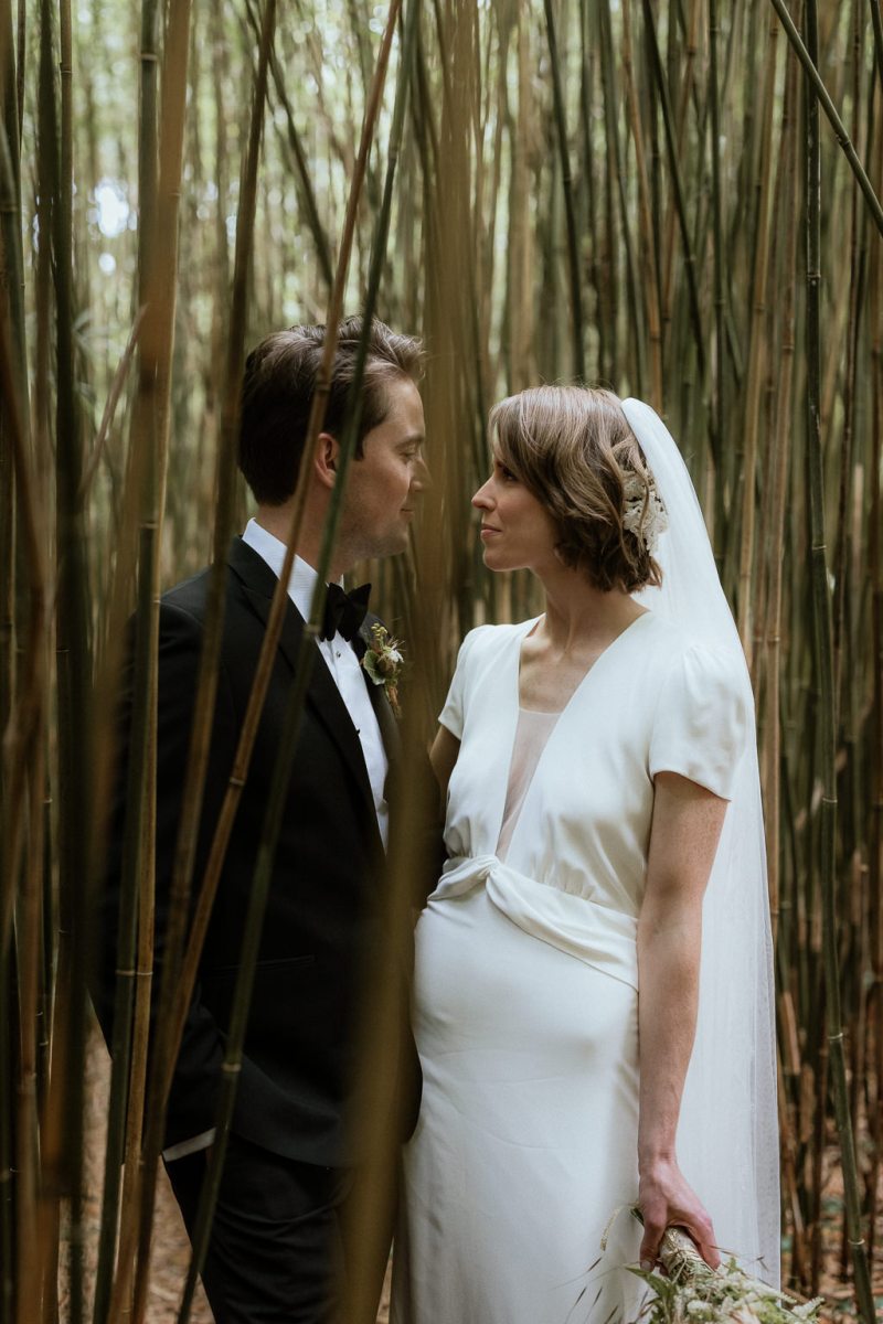 Bride and groom celebrating laughing in forest trees bouquet