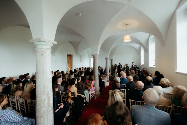 Guests look at bride and groom as they're seated during ceremony