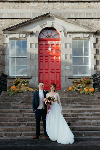 Bride and groom stand on steps to wedding venue