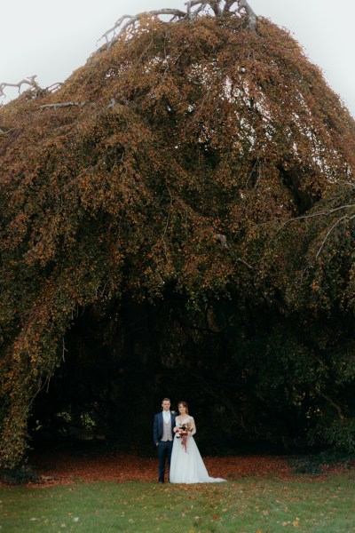 Bride and groom walk through forest moody shot