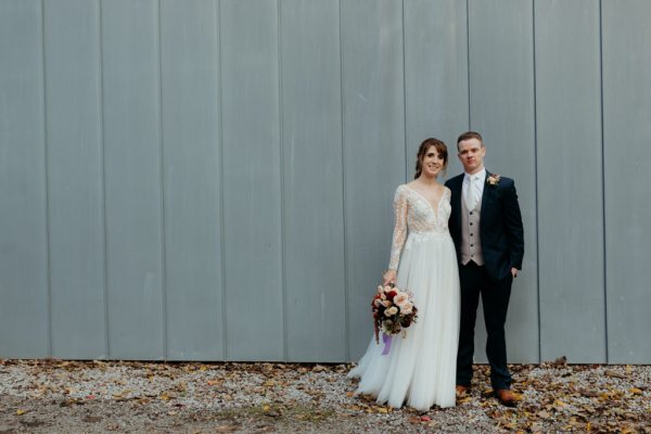 Groom hand in pocket bride has arm around groom