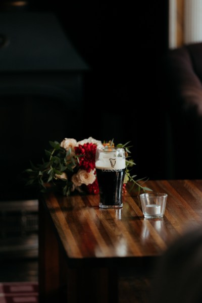 Pink of Guinness in front of red rose and candle holder