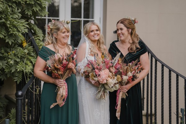 Bridesmaids and bride holding bouquet of flowers on steps