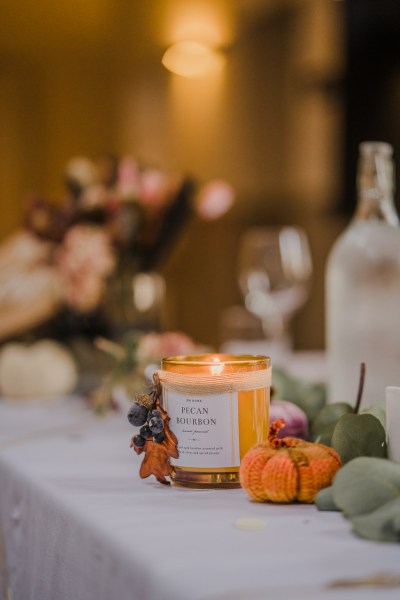 Candle lighting flowers surrounding it on table