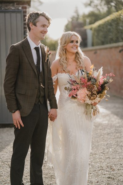 Bride and groom smile hand in hand