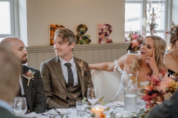 Bride laughs at table in dining room with groom