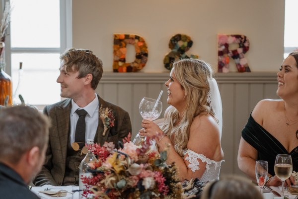 Bride laughs at table in dining room with groom