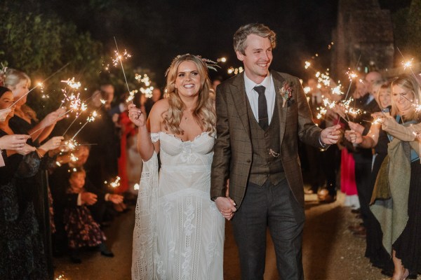 Bride and groom smile laugh holding sparklers