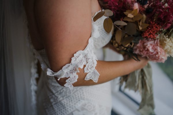 Close up of the brides lace dress off the shoulders detail gown