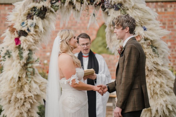 Bride groom and officiant holding hands