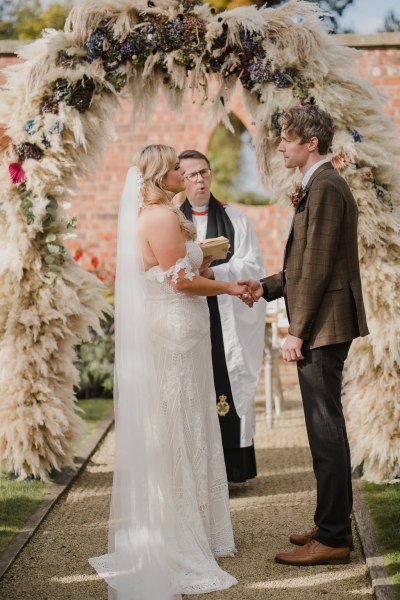 Bride groom and officiant holding hands