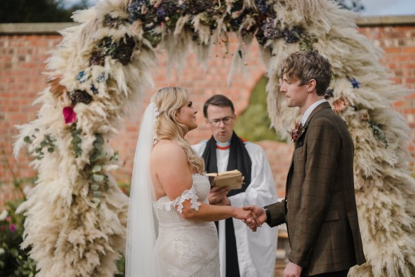 Bride groom and officiant holding hands