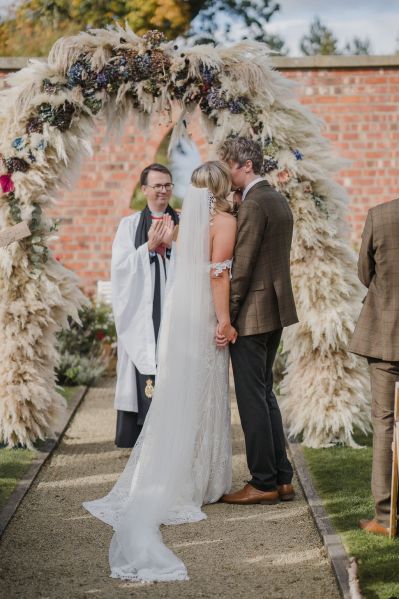 Bride and groom kiss at alter before priest