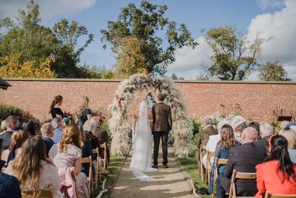 Bride groom priest at alter in front of guests