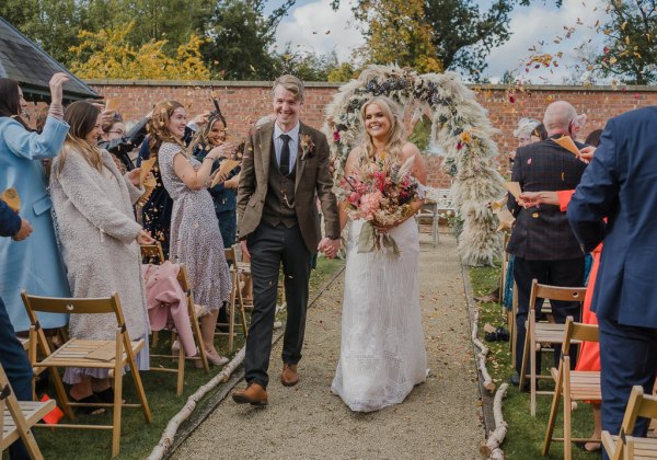 Confetti is thrown over the bride and couple as they exit ceremony