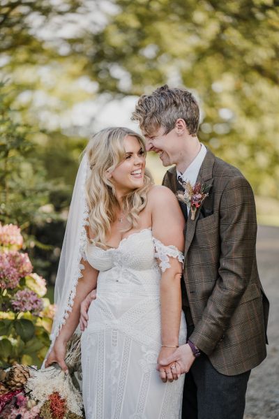 Bride and groom smiling at each other in garden forest setting