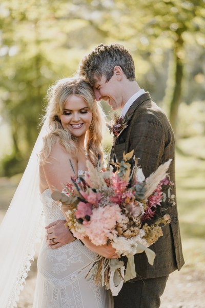 Bride laughs with groom holding bouquet flowers