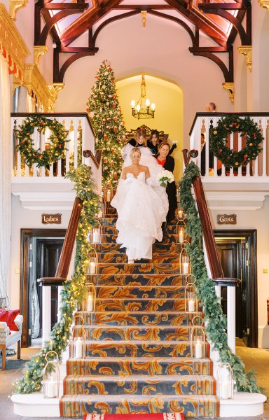 Bride and family members help her walk down the staircase stairs