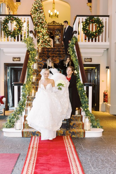 Bride and family members help her walk down the staircase stairs