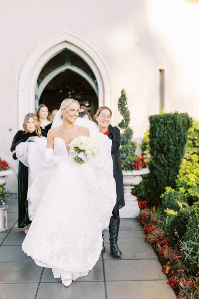 Bride gets help with her dress walking smiling