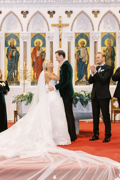 Bride and groom kissing kiss at alter smiling guests clapping