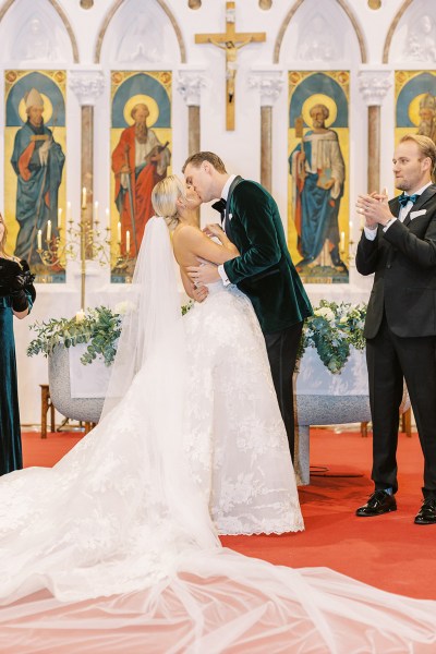 Groom kisses bride at the alter guests clap