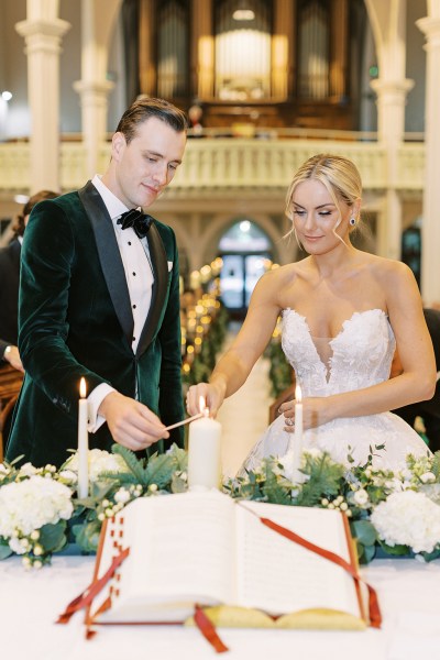 bride and groom smiling lighting the candles at alter