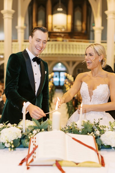 bride and groom smiling lighting the candles at alter laughing