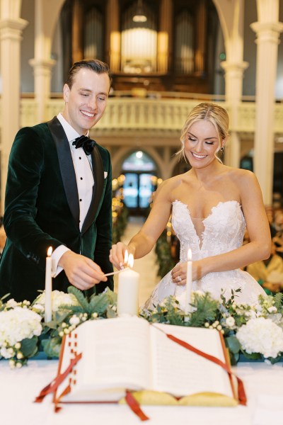 bride and groom smiling lighting the candles at alter