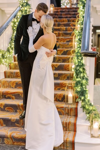 Groom places hand on back of bride bow ribbon white dress gown detail