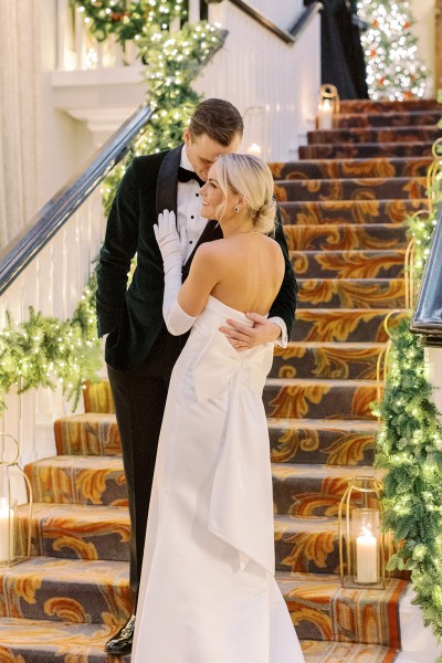 Groom places hand on back of bride bow ribbon white dress gown detail