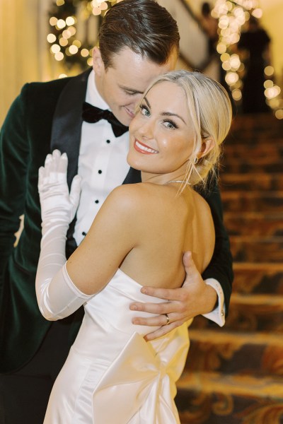 Groom places hand on back of bride bow ribbon white dress gown detail over the shoulder