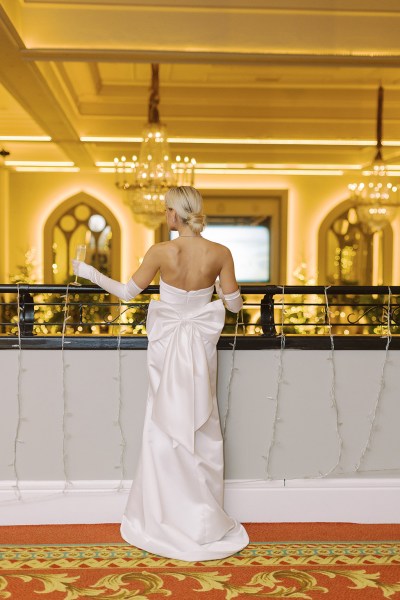 Bride from behind stands at balcony showing off glove detail