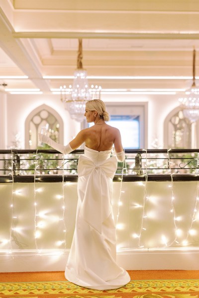 Bride from behind stands at balcony showing off glove detail