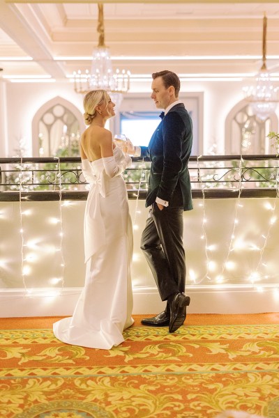 Bride and groom stand at balcony surrounded by lights