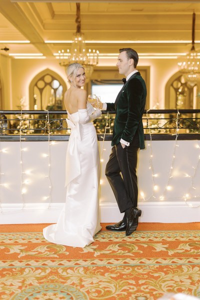 Bride and groom stand at balcony surrounded by lights