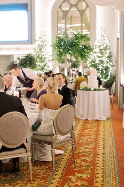 Atmosphere shot of guests seated in dining room and bride and groom at table